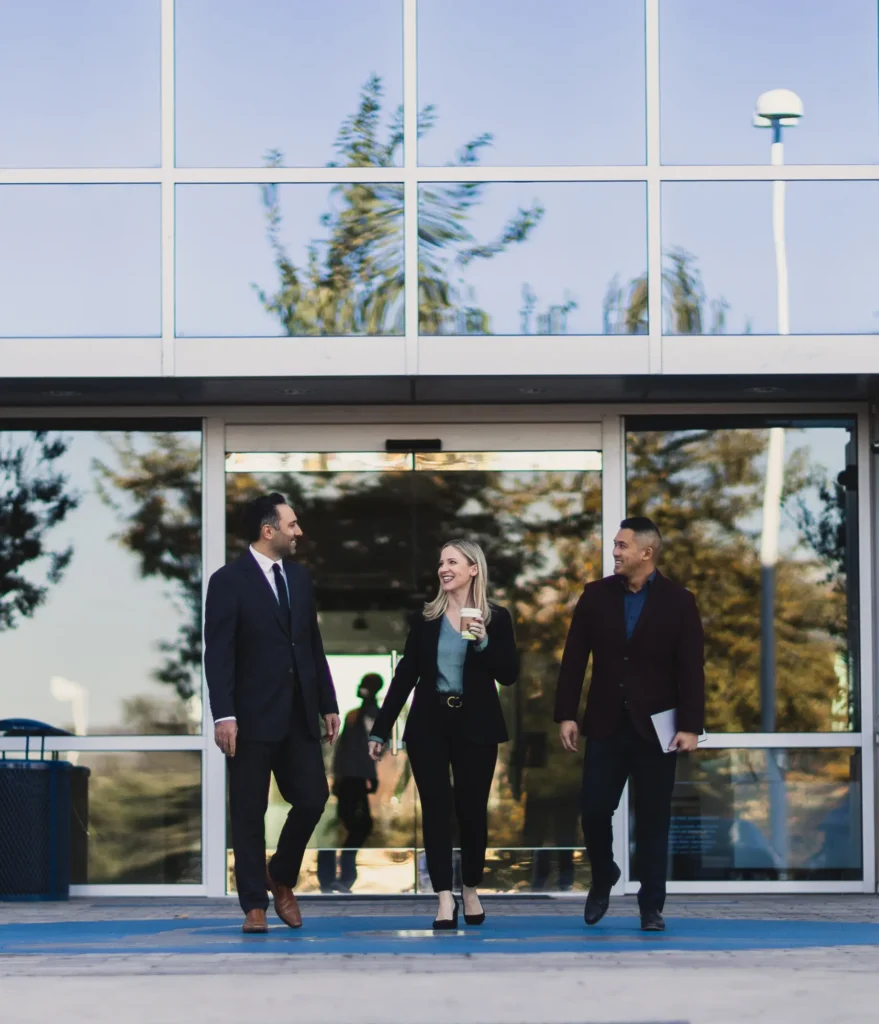 Three professionals walking outside building.