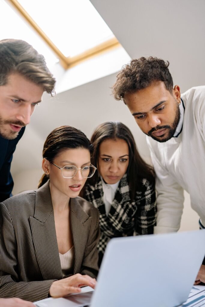 A diverse team of specialists collaborating on a laptop in a modern office